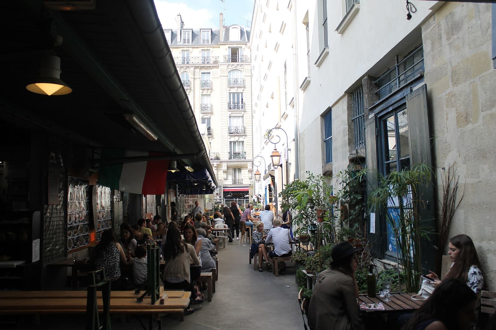 Diners at shared tables in a busy alley of the Marché des Enfants Rouges