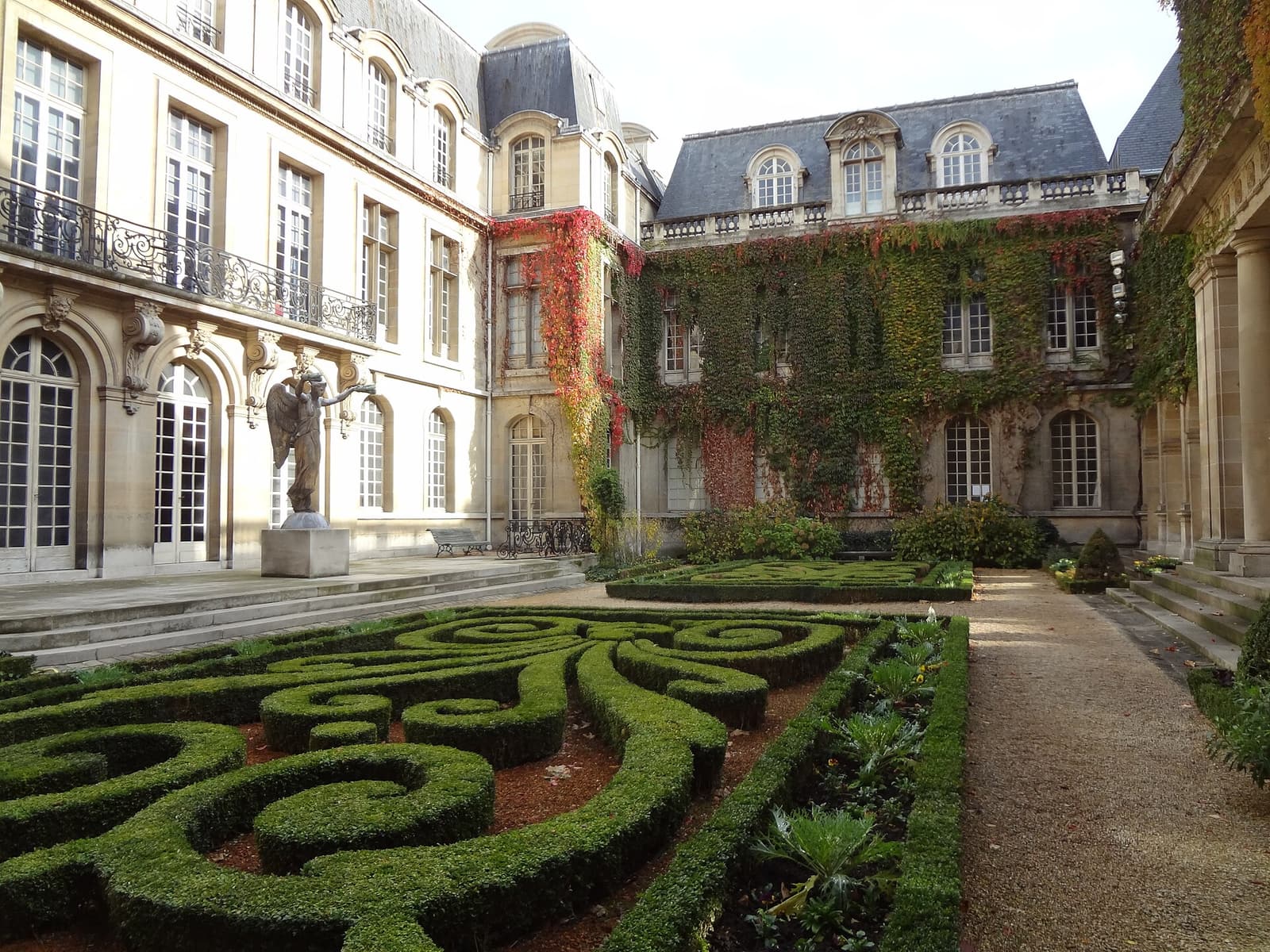 The formal box-hedge garden of the Musée Carnavalet surrounded by mansion walls