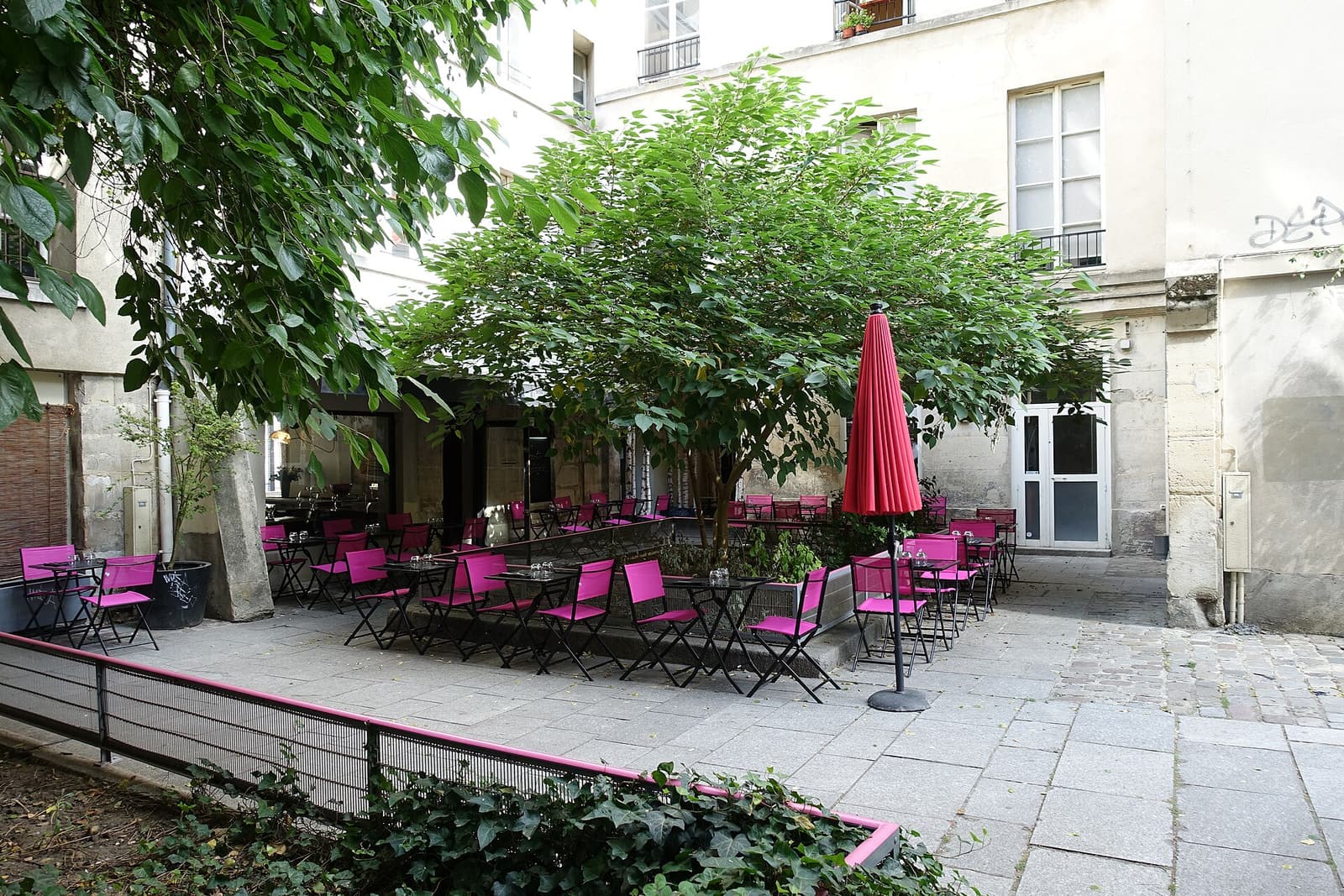 A quiet courtyard of Village Saint-Paul with pink café chairs under a tree