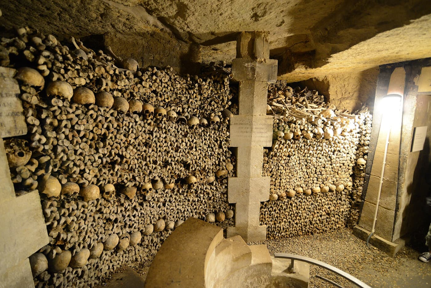 Walls of stacked bones and skulls lining a tunnel of the Paris Catacombs