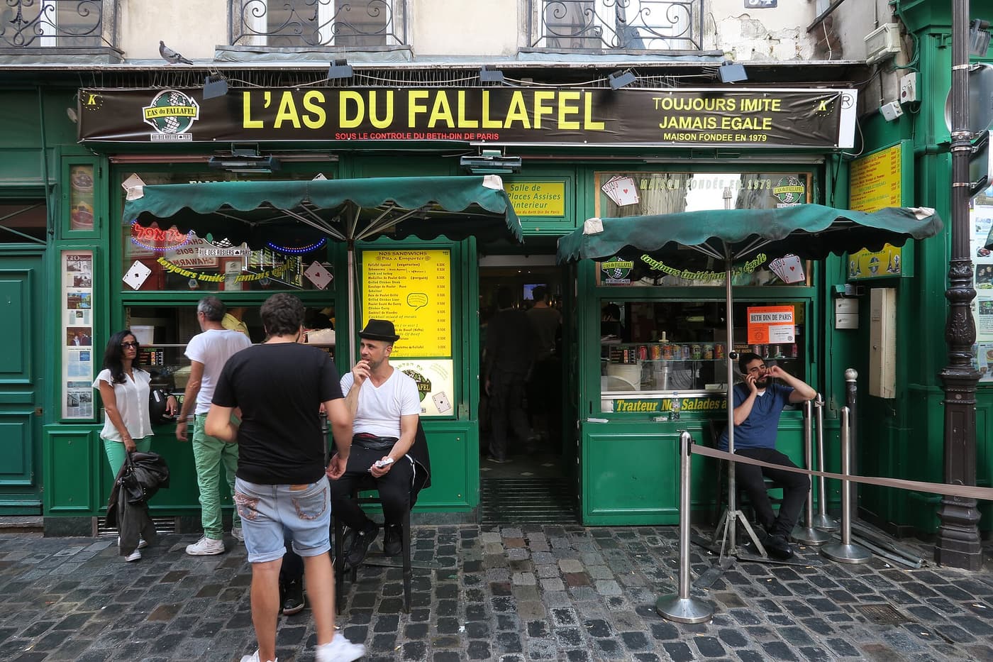 The green shopfront of L’As du Fallafel on Rue des Rosiers with customers waiting outside