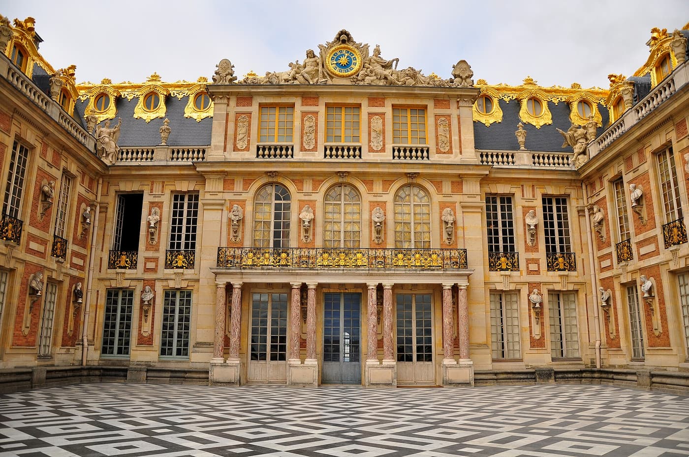 The Marble Courtyard of the Palace of Versailles with its gilded balcony and clock
